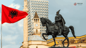 Fotografía de la plaza Skanderbeg en Tirana Albania. Plano directo a la estatua de Skanderbeg y a la bandera de Albania. De fondo se ven edificios propios de la ciudad