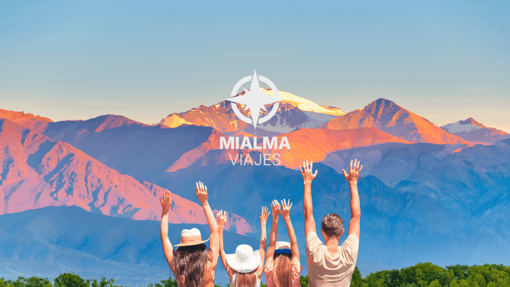 Fotografía de paisaje montañoso en Argentina con familia de cuatro de espaldas con los brazos en alto. En el centro Logo de Mialma Viajes, agencia de viajes especializada en viajes organizados en familia. 