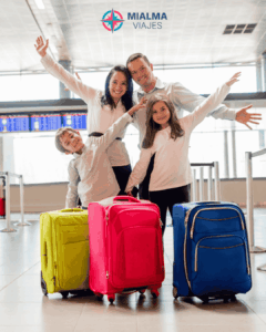 Fotografía de familia de madre y padre con dos niños en el aeropuerto con tres maletas. 