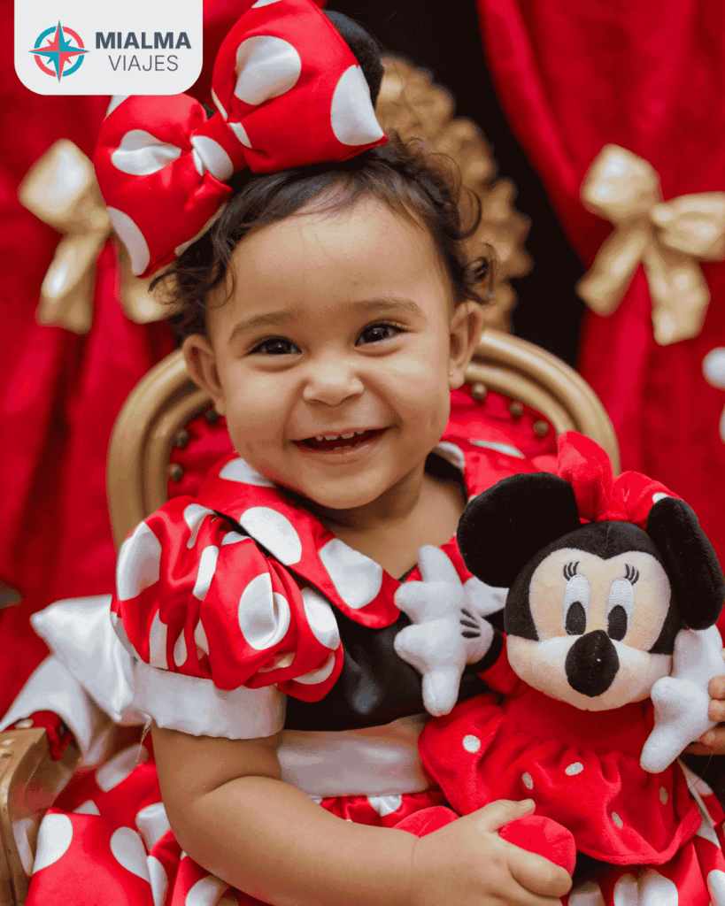 Fotografía de niña disfrazada de Minie Mouse con peluche del personaje.