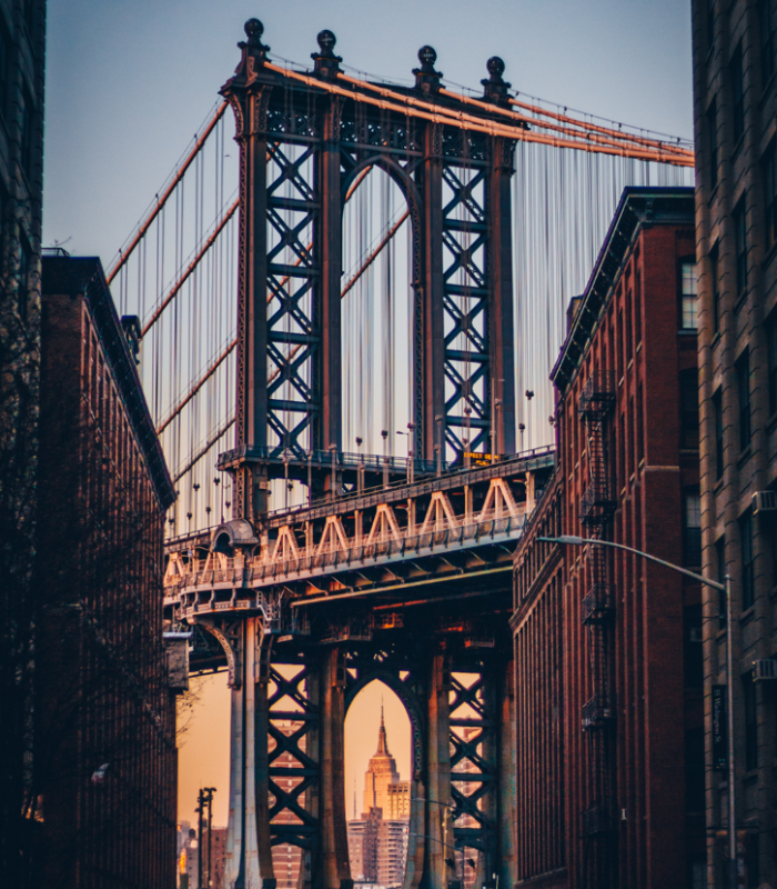 Puente clásico de Nueva York con arquitectura histórica y fondo urbano al atardecer.