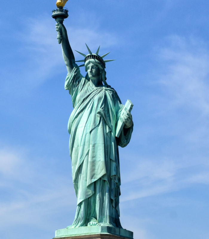 Estatua de la Libertad en Nueva York con cielo despejado, símbolo de libertad y bienvenida.