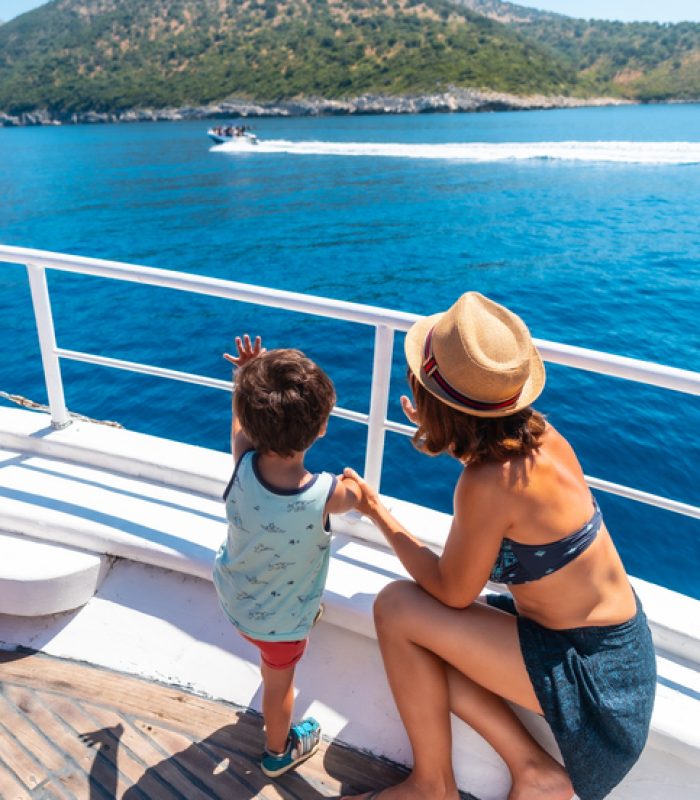 Mother and son tourists playing along the Gremina beach seen from the boat on the Albanian riviera near Sarande and its turquoise waters, Albania